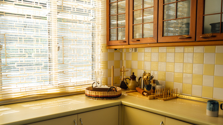 A closed vintage kitchen with wooden cabinets and yellow countertops