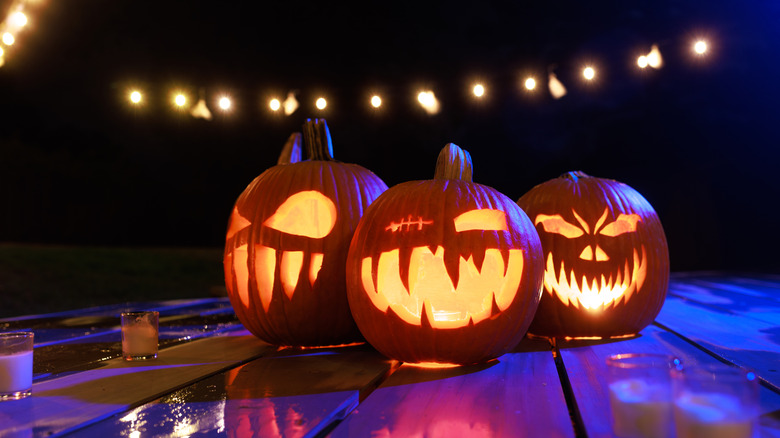 Three carved pumpkins on a deck.