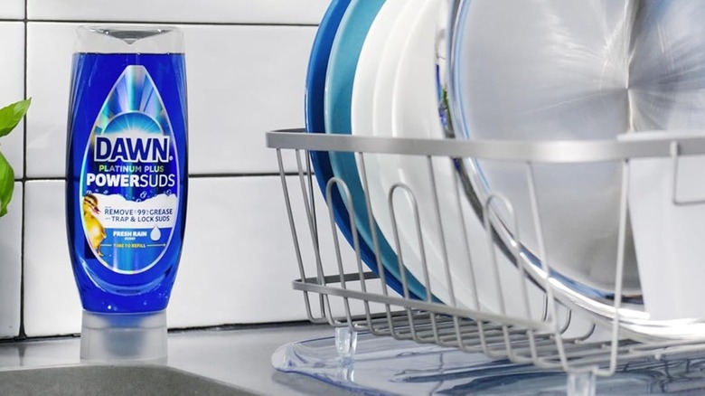 Dawn Platinum Plus Liquid Dish Soap next to a sink and a drying rack full of dishes