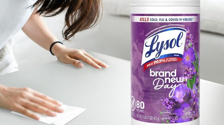 Someone using Lysol Brand New Day Lavender & Cotton Blossom Disinfecting Wipes on a table