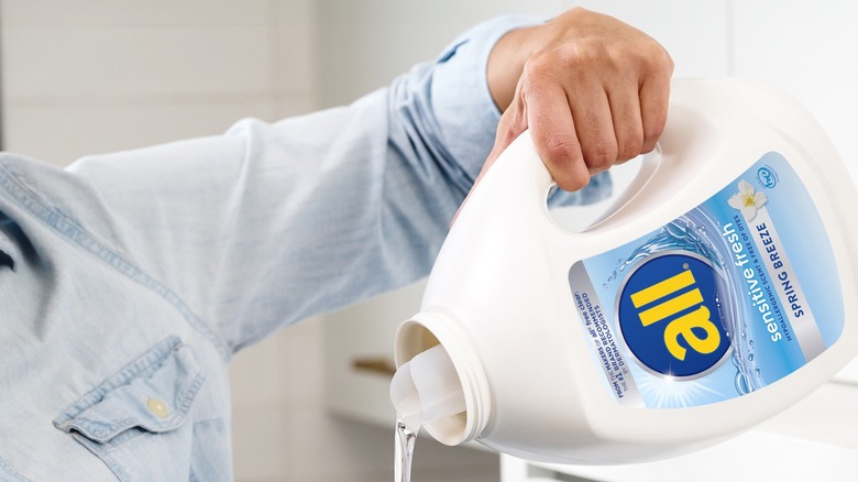 Someone pouring All Sensitive Fresh Spring Breeze HE Liquid Laundry Detergent from the bottle