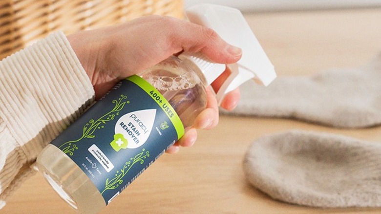 Someone spraying Puracy Stain Remover Spray onto a sock