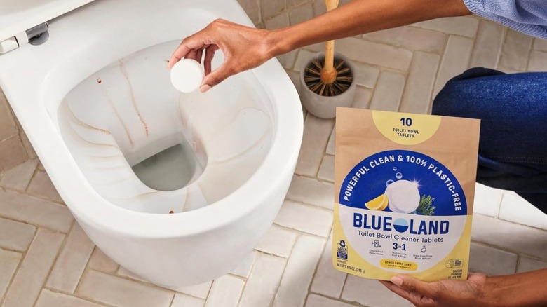 Someone putting Blueland Toilet Bowl Cleaner Table into a dirty toilet