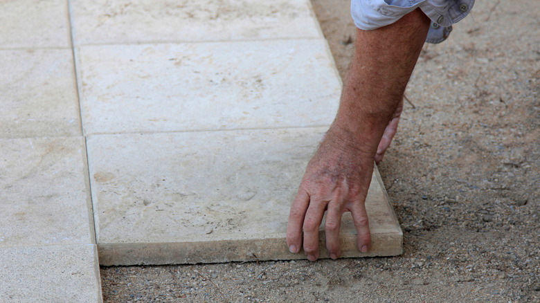 A man laying porcelain pavers for a driveway