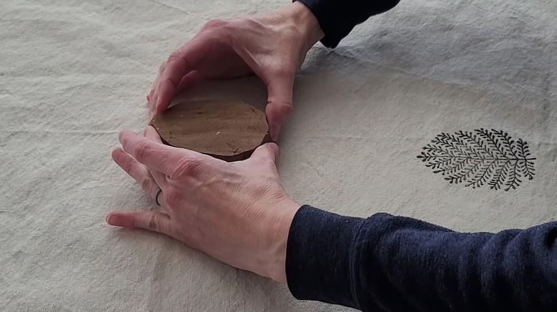 Woman pressing a wooden printing block over a white curtain