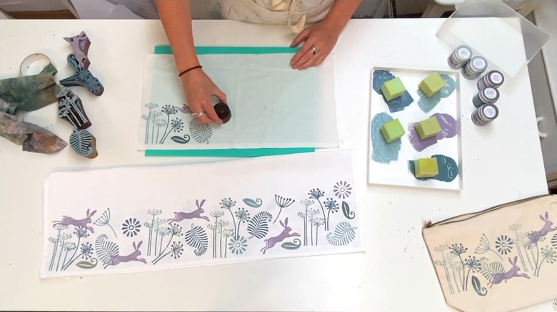 Woman pressing different kinds of wooden printing blocks over a small piece of cloth