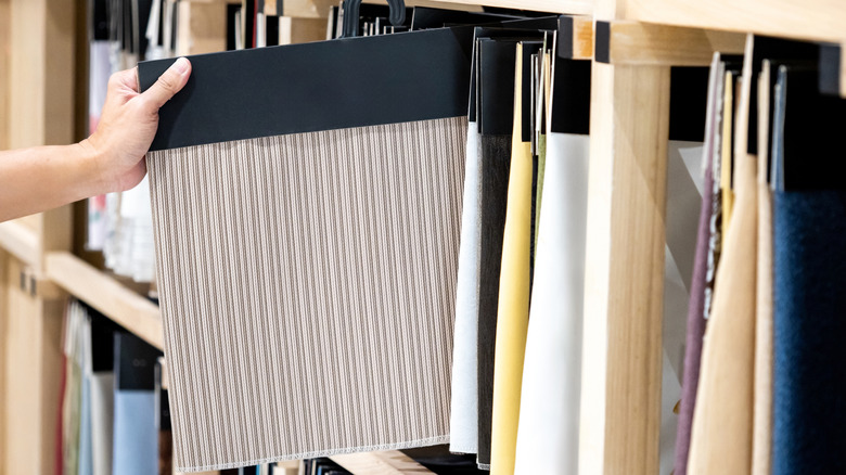 A hand picking out one of dozens of fabric samples for a curtain