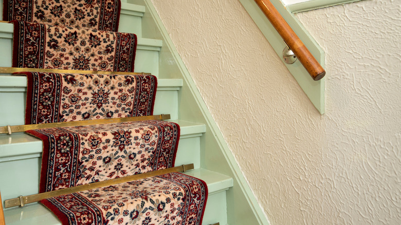 Vintage patterned carpet as a staircase runner on mint green stairs