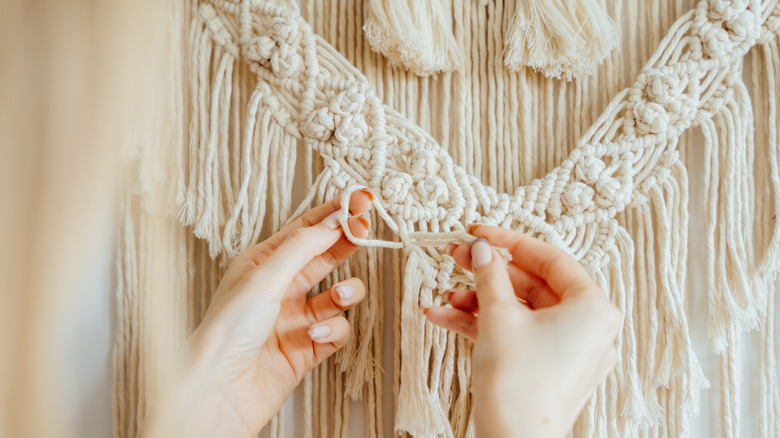 A woman weaving a macrame hanging