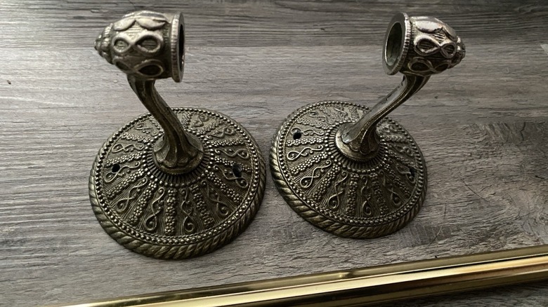 A pair of brass Contessa design midcentury towel rail brackets and a rail set on a wooden tabletop.