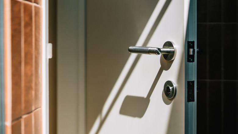 Close up of a plain, white door cracked open.