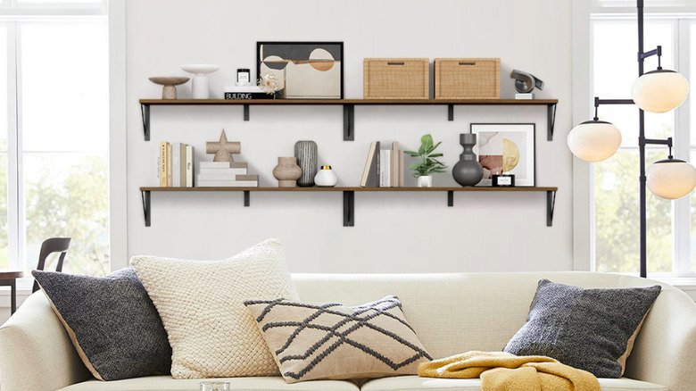 Floating bookshelves behind a big white couch.