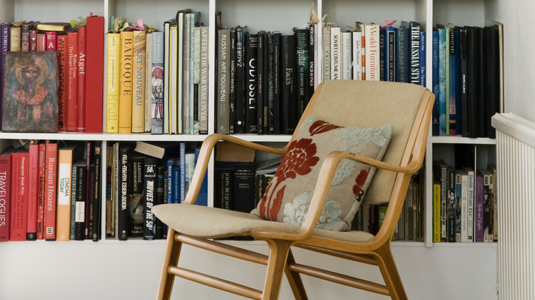 A tan chair in front of a white bookcase.