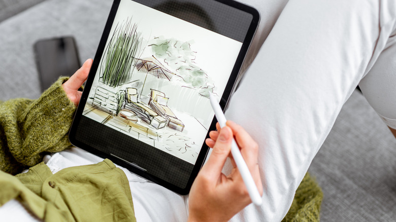 A person holds a stylus while designing a new patio on a tablet.