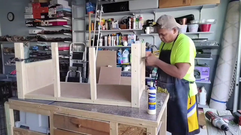 A man assembles a dog crate bench DIY in his woodworking shop