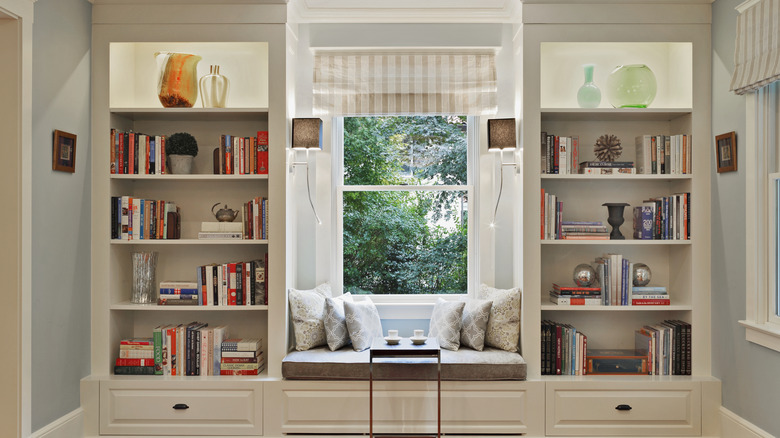 Two open shelves on either side of a window filled with books and other decor