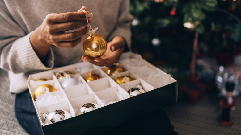 Person's hands taking out or putting away gold bauble ornament
