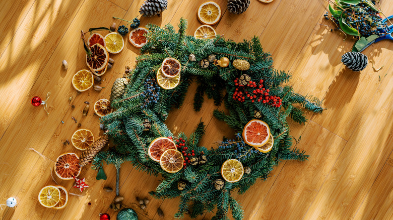 Dried orange slices arranged around evergreen wreath on floor