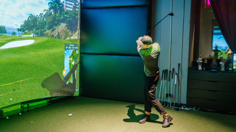 Man using a golf simulator indoors.