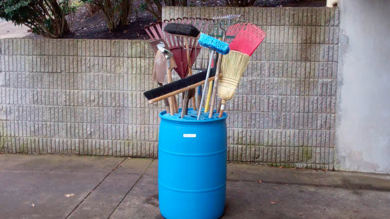 A plastic barrel holding garden tools