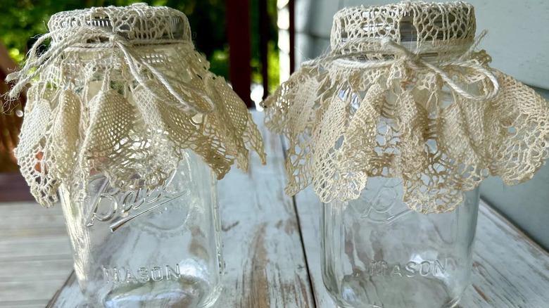 Two mason jars with doilies tied around the lids.