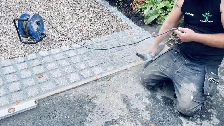 Man working on adding a rumble strip to a gravel driveway.
