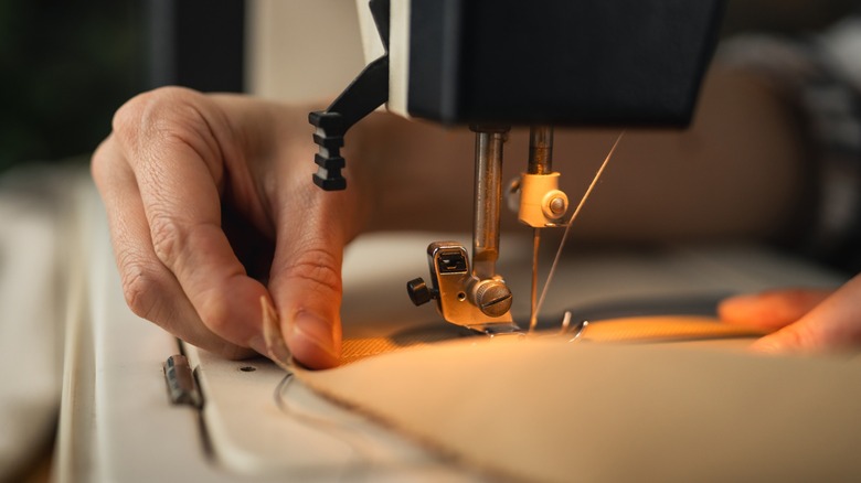 Hands guiding fabric under a sewing machine