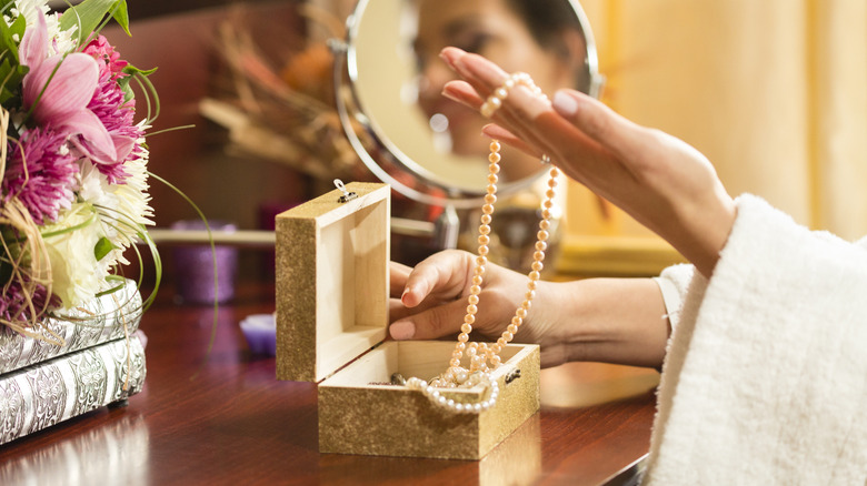 Woman pulling necklace out of jewelry box
