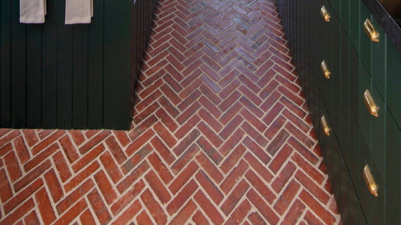 Brick herringbone floor with green cabinets in kitchen design