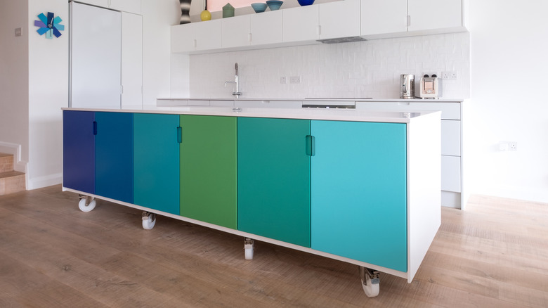 Kitchen cabinet with blue and green door panels on wheels