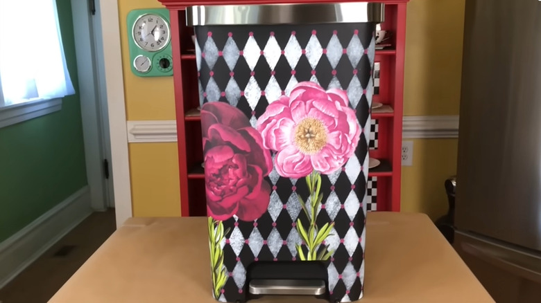 Hand-painted trash can with a black and white diamond pattern and large pink and red flowers