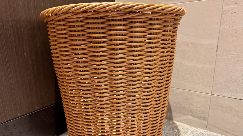 A round wicker basket being used as a trash can