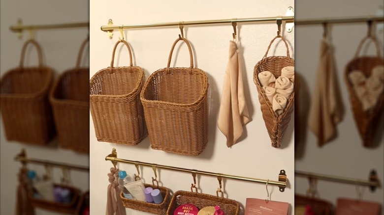 Brass rails with hanging wicker baskets mounted on a wall in a bathroom