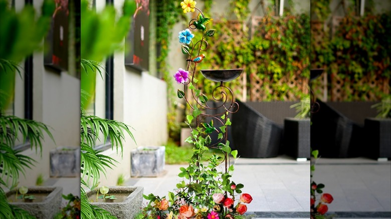 a metal bird bath and trellis combo with a hummingbird design