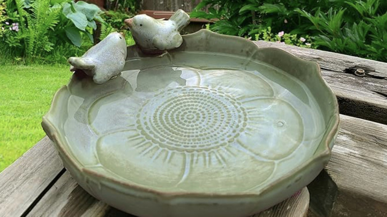 A Bakayoyo bird bath on a wooden deck with water