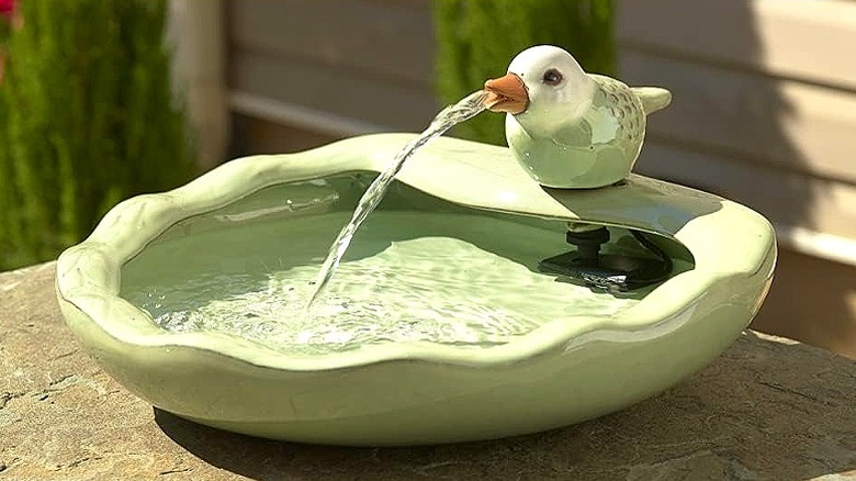 A sage green solar bird bath with flowing water feature