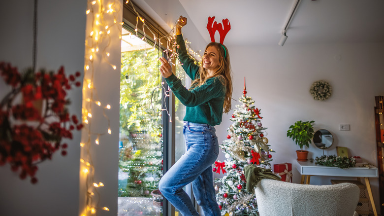 Woman hanging Christmas lights around a window