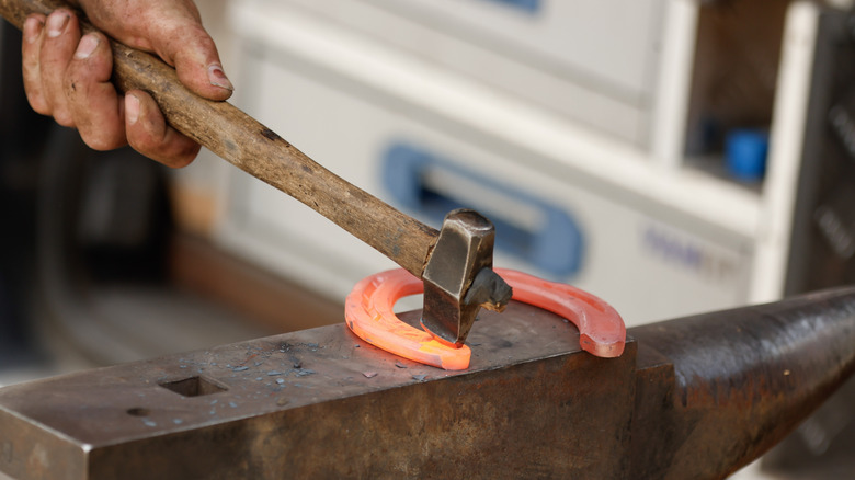 A person using a hammer on a heated horseshoe