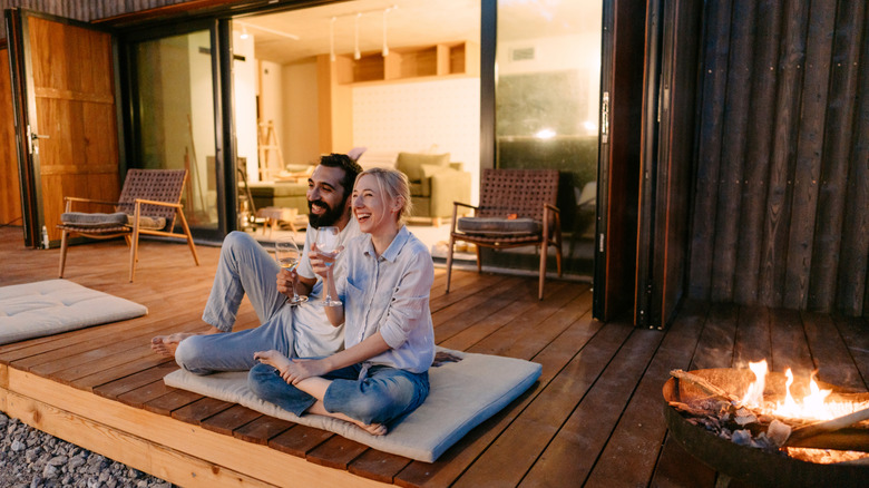 couple sitting outside on patio beside fire