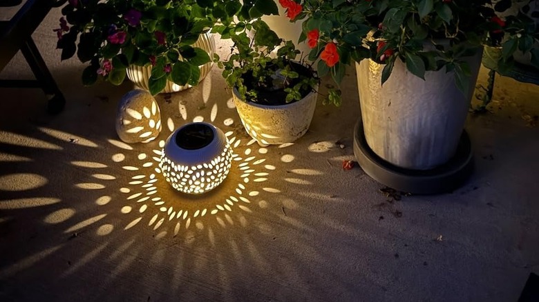 a white solar outdoor lantern placed beside plants