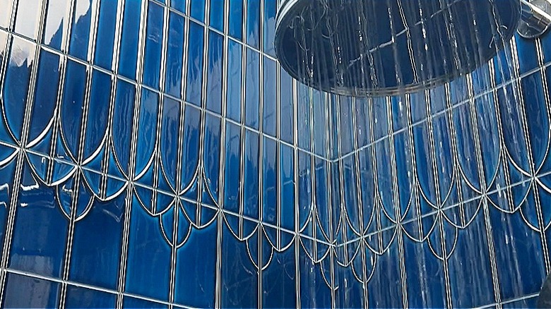 Navy art deco shower tiles seen with a rainfall showerhead