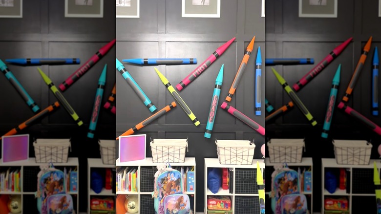 Giant crayons made from pool noodles hanging on kids' room wall.