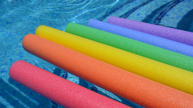 Colorful pool noodles sitting out by the pool.
