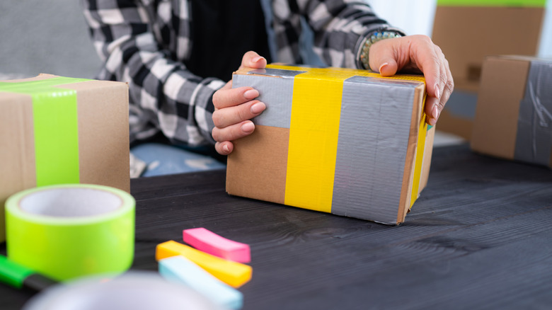 A person wrapping boxes with colorful duct tape