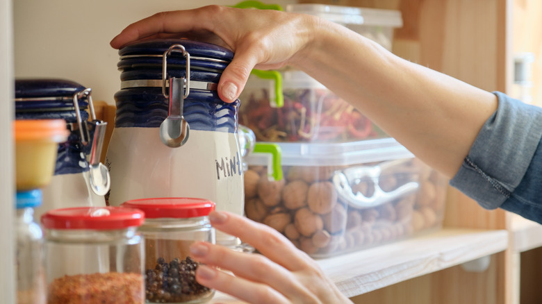 woman sorts through crowded pantry