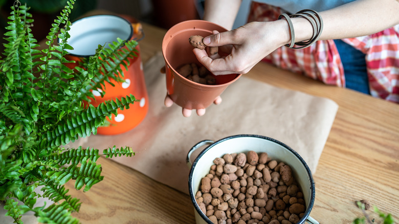 A person puts clay inside of a pot for a plant