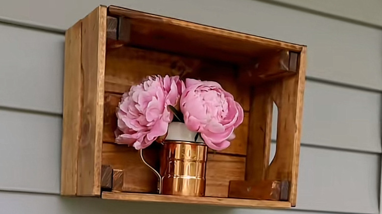 Wooden box with flowers in a copper cup hanging on an exterior wall