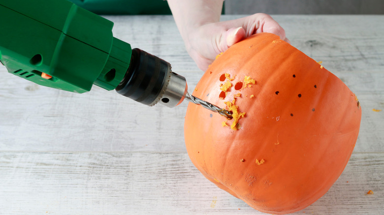 person drilling pumpkin