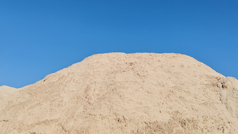 A large mountain of fill sand in front of a clear blue sky