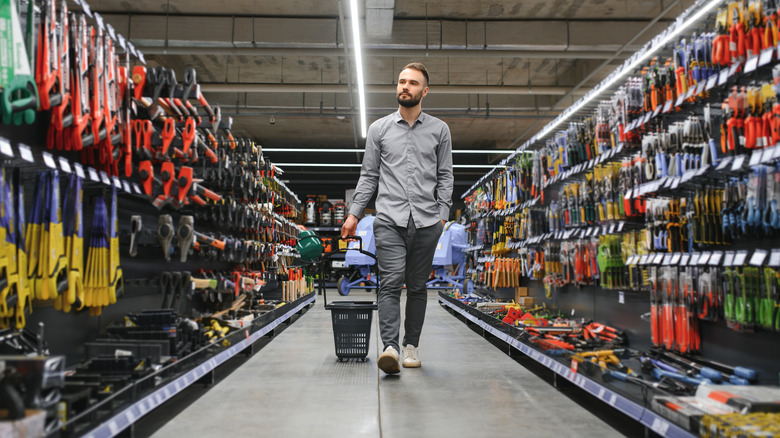 A man with a cart shopping in a hardware store